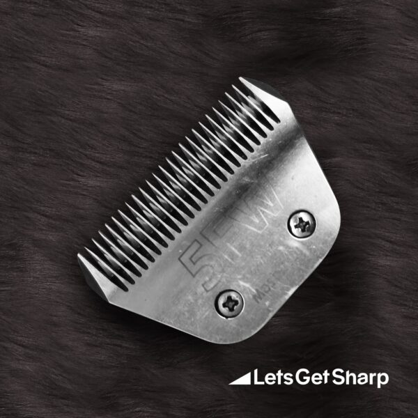 Wide grooming clipper blade on a black fur background after being sharpened
